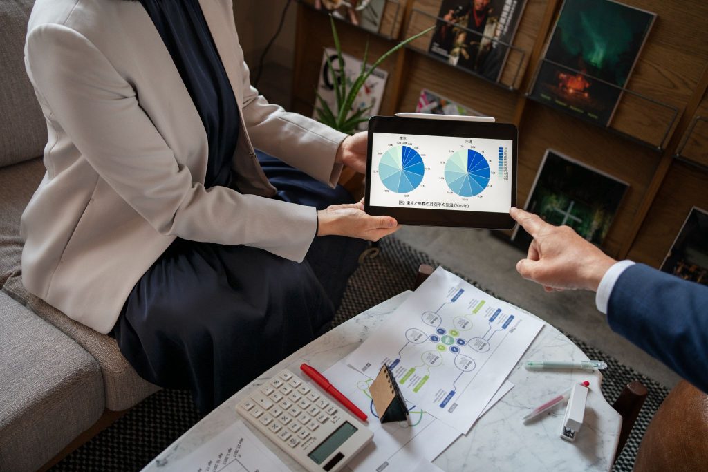 Professionals reviewing charts on a tablet with business reports on a table